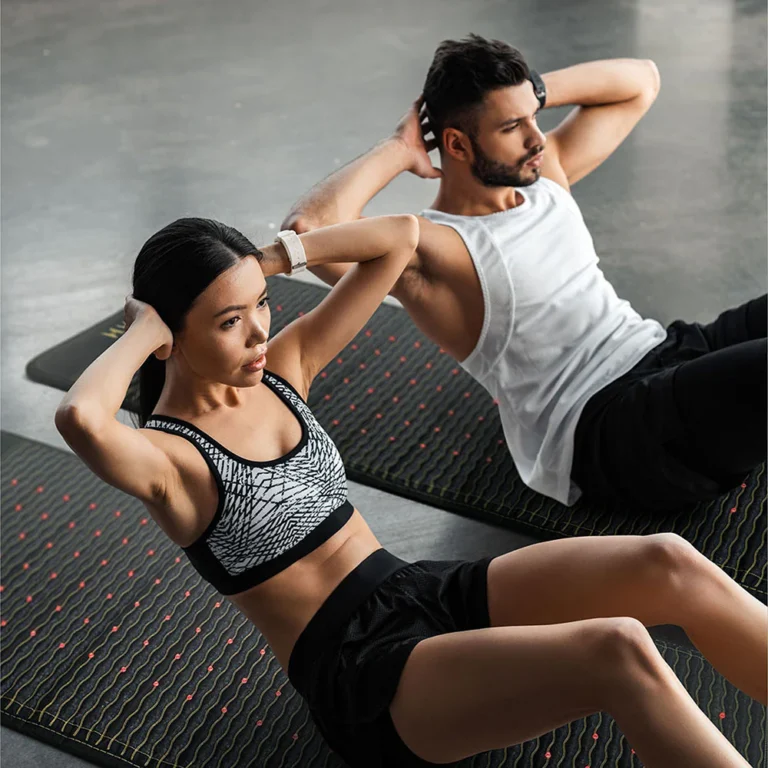 A man and a woman doing sit ups on HealthyLine natural gemstone heat therapy mats