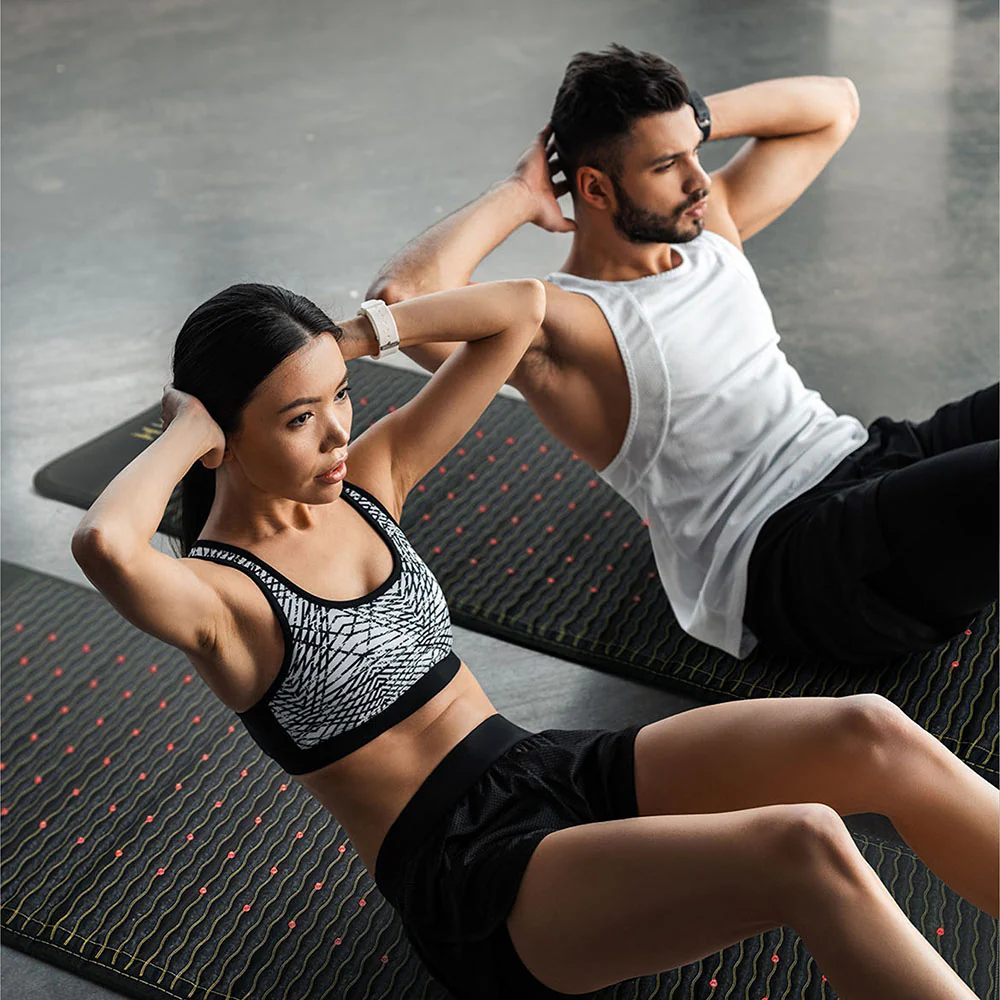 A man and a woman doing sit ups on HealthyLine natural gemstone heat therapy mats