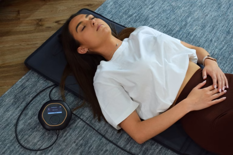 Woman lying on a CELLER8 PEMF mat during a home wellness session