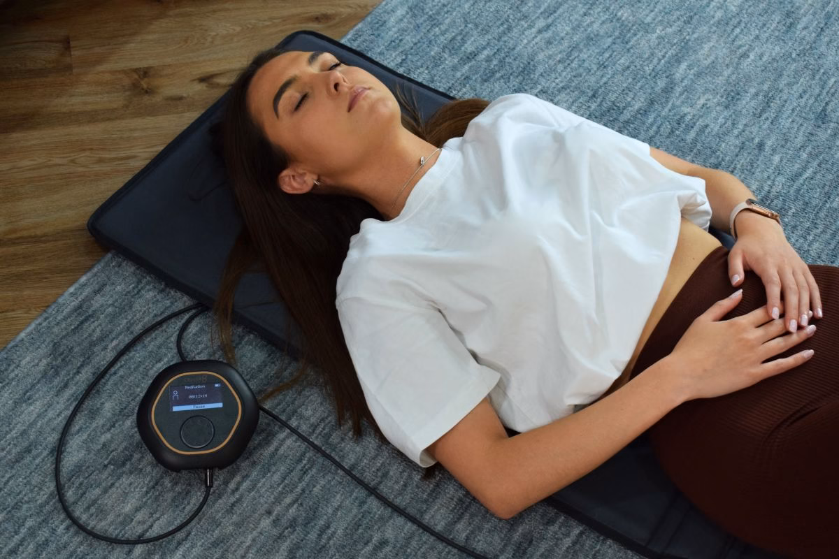Woman lying on a CELLER8 PEMF mat during a home wellness session